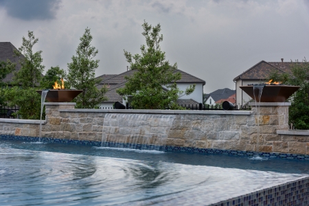 Two firepits flanking a stone waterfall