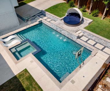 aerial view of a pool with spa, hoops, and a shell seat