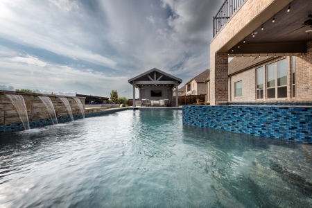 Outdoor cabana with waterfalls into a pool