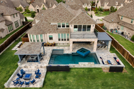 Aerial view of a sunken firepit, spa and pool with an outdoor kitchen