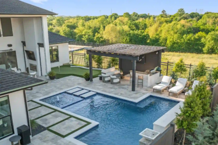 High view of a swimming pool and outdoor kitchen amidst a forest