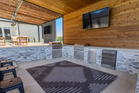 Outdoor kitchen with wood paneling and a tV